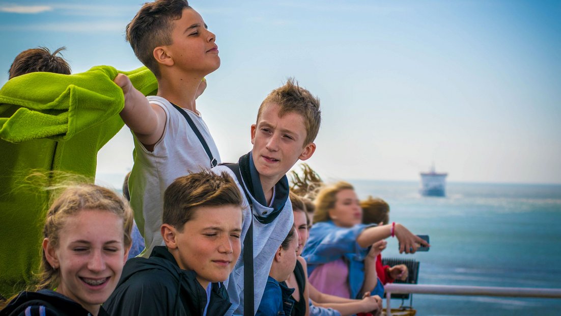 Mladi ljudi na palubi broda uživaju u pogledu.