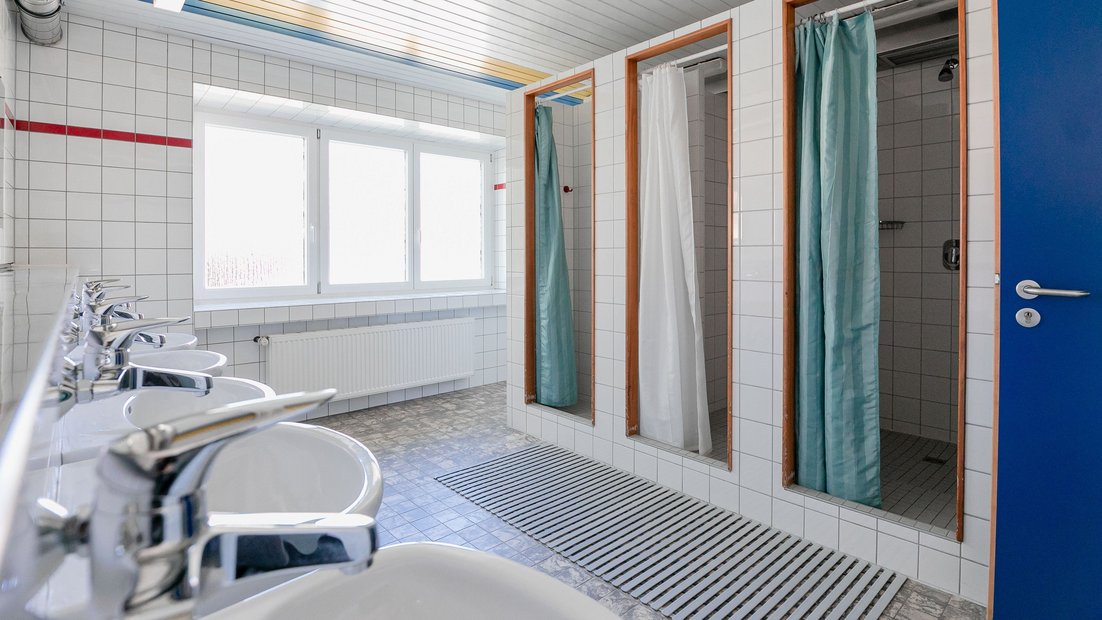 Belo pločasto kupatilo u letnjikovcu sa više lavaboa i tuševa