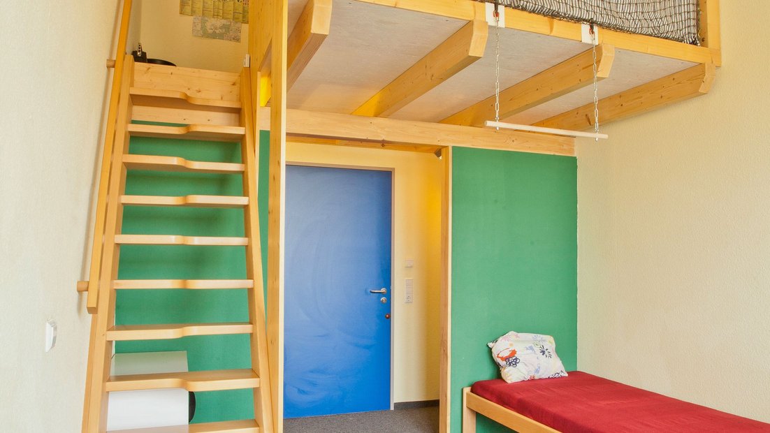 Соба у кући на ливади са креветом и дрвеним степеништем