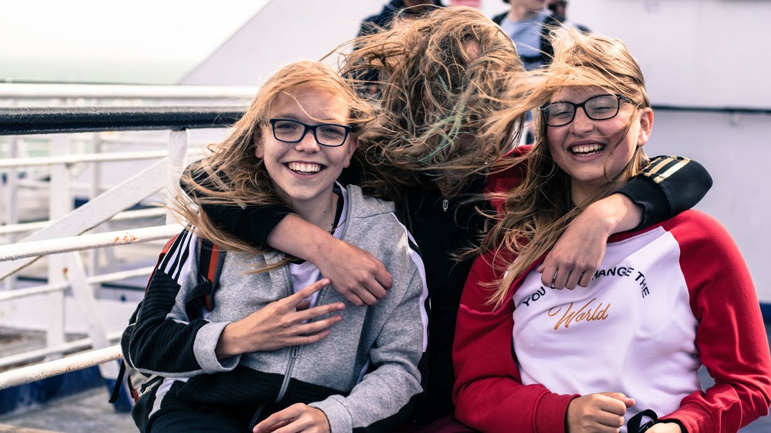 Tri devojke na palubi broda se smeju u kameru.